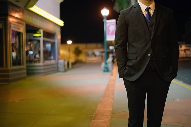 夜の街を歩くスーツ姿の男性
