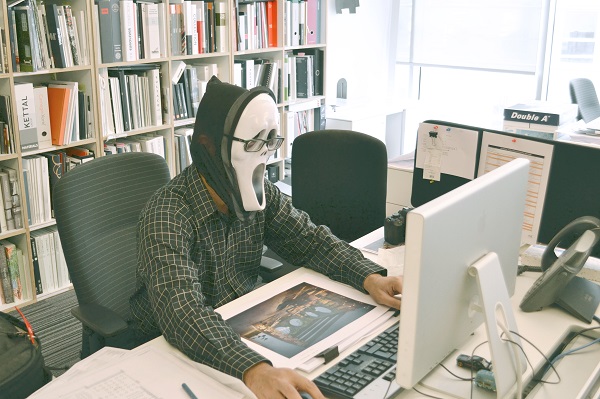 マスクを被ってパソコンを見る男性